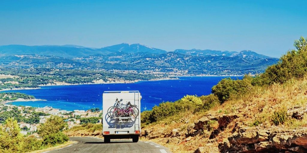 Camper in viaggio su una strada costiera, con il golfo sullo sfondo